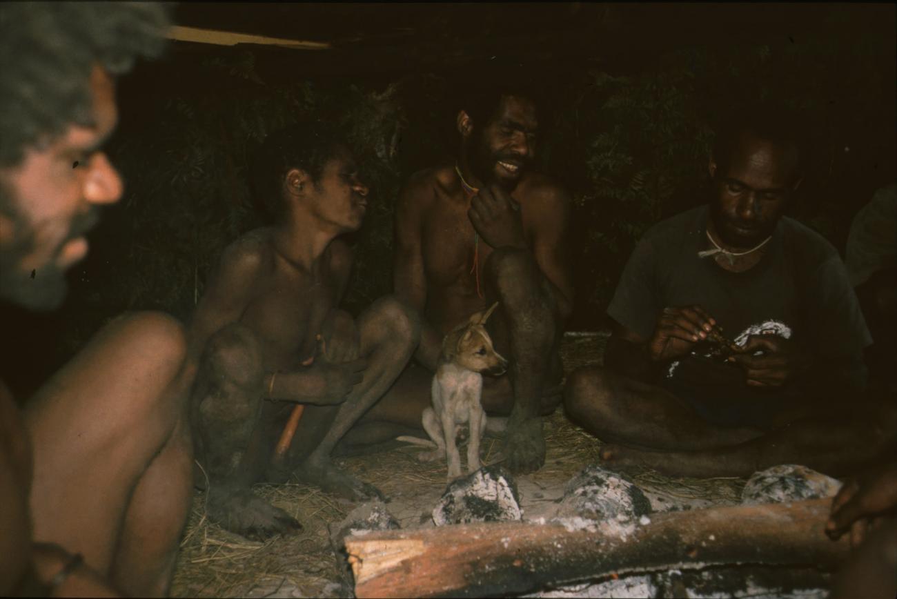 BD/166/109 -
Dog with men in circle around wood fire