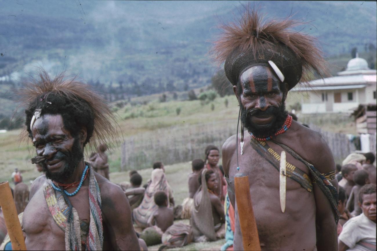 BD/166/123 - 
Two men with feathers and black stripes on their faces
