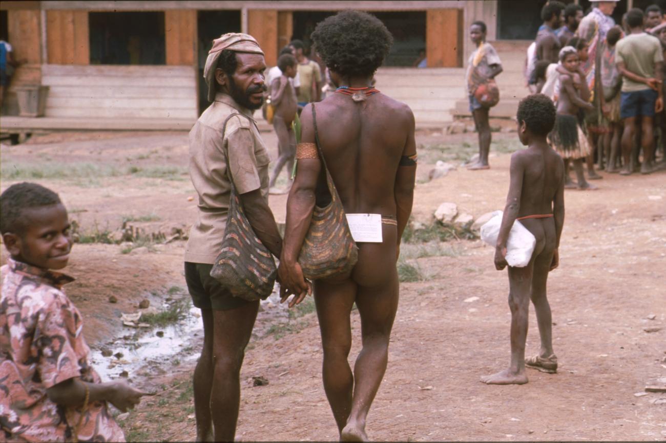 BD/166/60 - 
Man in traditional clothes and paper hanging on a thread on his lower back
