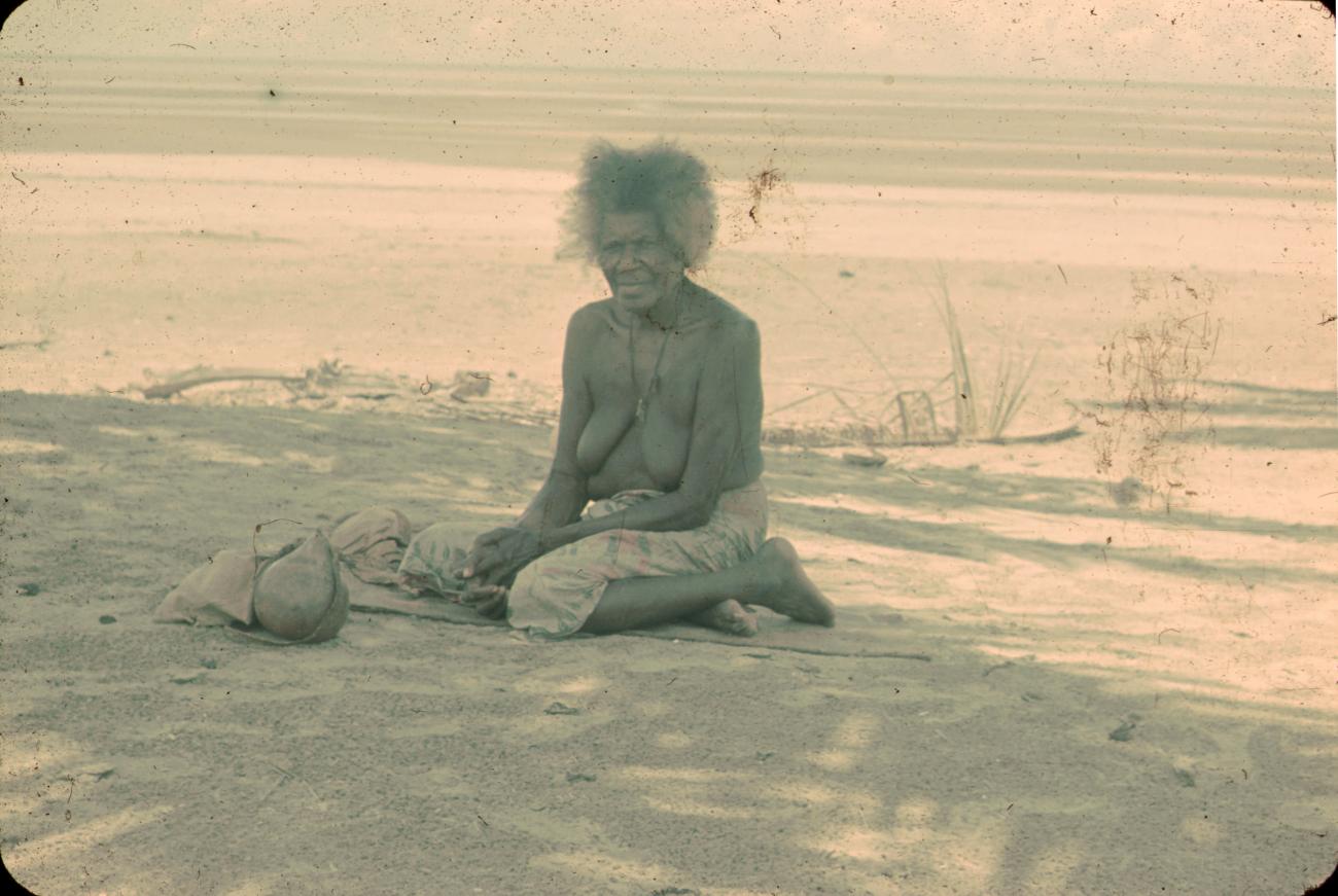 BD/288/165 - 
Oude vrouw zit aan het strand
