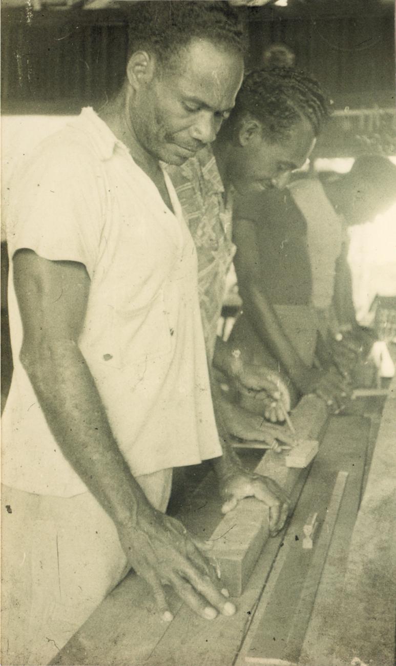 BD/309/61 - 
Dorp Teminabuan, mannen bezig met houtbewerking

