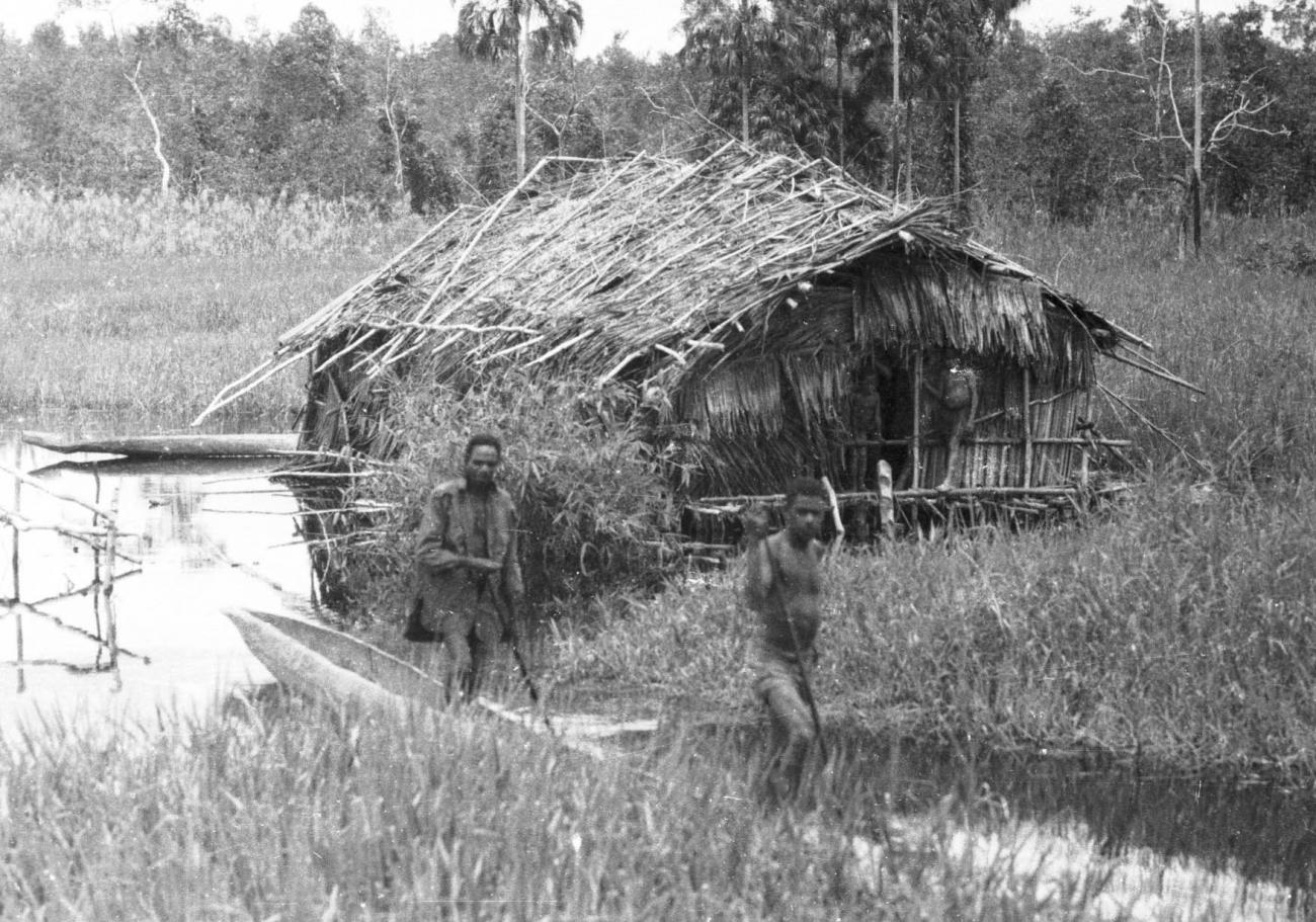 BD/133/421 -
Tocht Merauke-Kepi-Cookrivier vv: Bemande prauw bij een hut aan de rivier