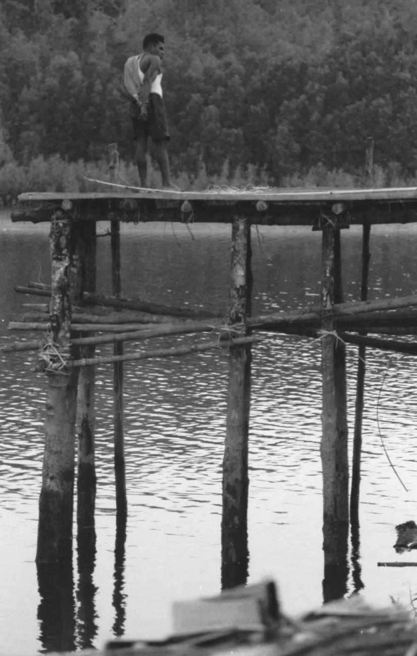 BD/133/66 -
Tocht Merauke-Kapi: Man op steiger aan de rivier