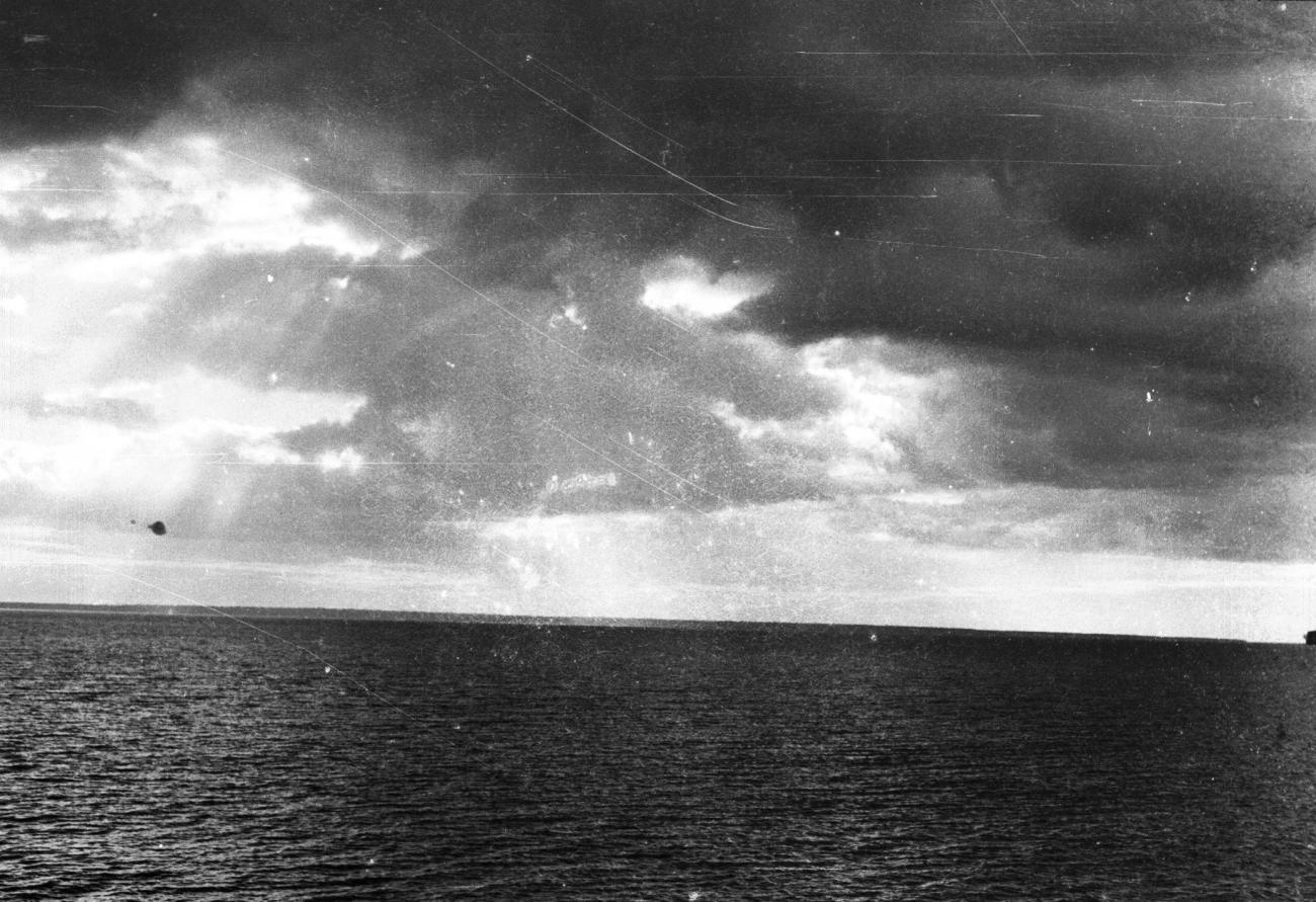 BD/133/855 - 
Kalme zee met kustlijn en donkere wolken
