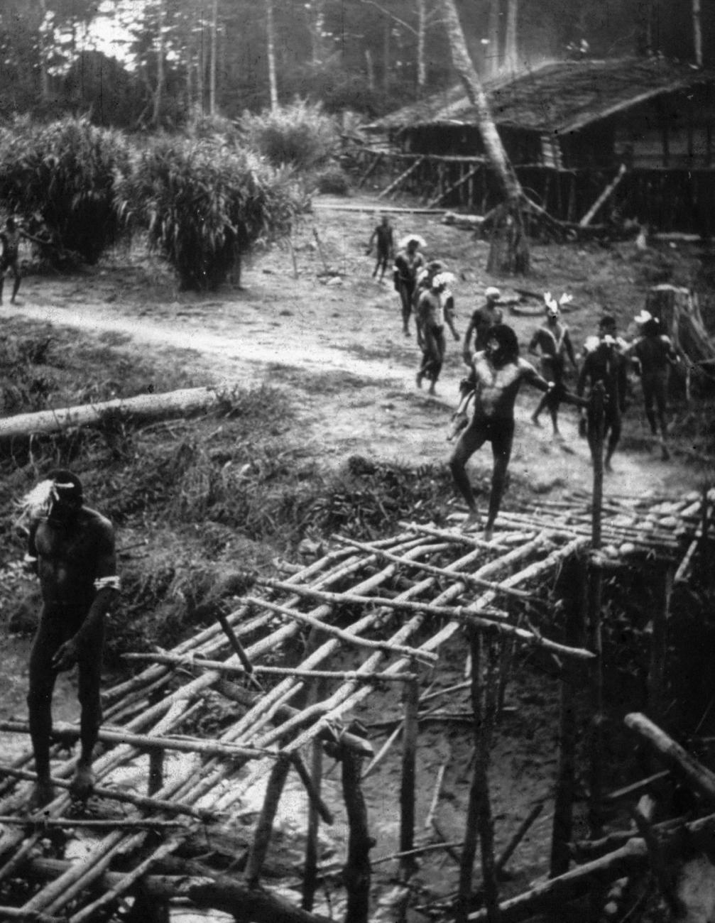 BD/216/118 -
Mannen lopen op een oude voetbrug van stammetjes over een water