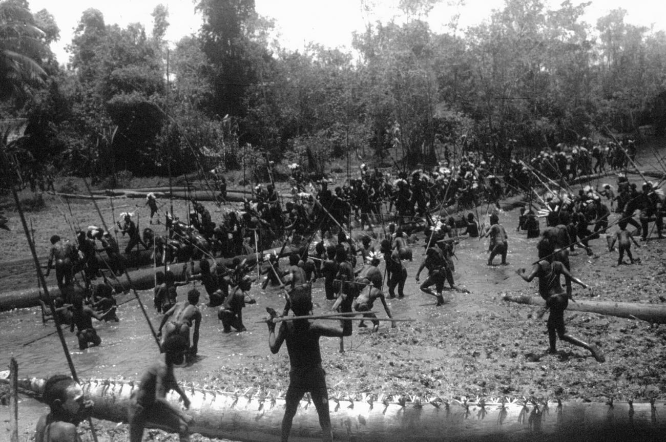 BD/216/138 -
Menigte Asmatters met verentooi en prauwen in rivier