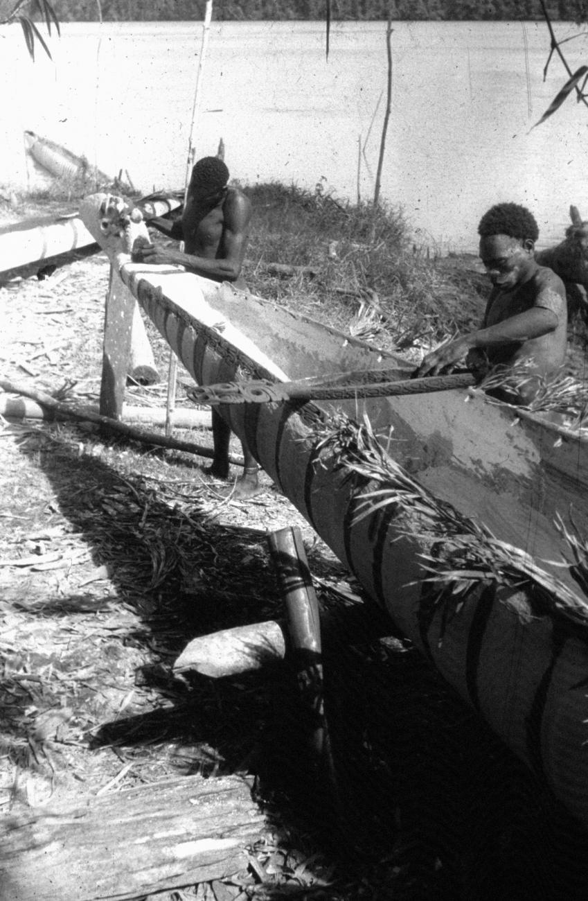 BD/216/196 -
Asmatters bezig met schuren en inkleuren met pigment aan een prauw