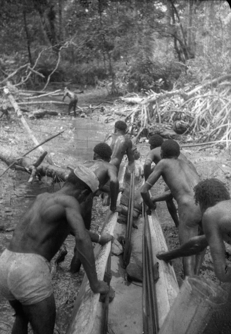 BD/216/235 -
Mannen vervoeren prauw over een drooggevallen stuk rivier
