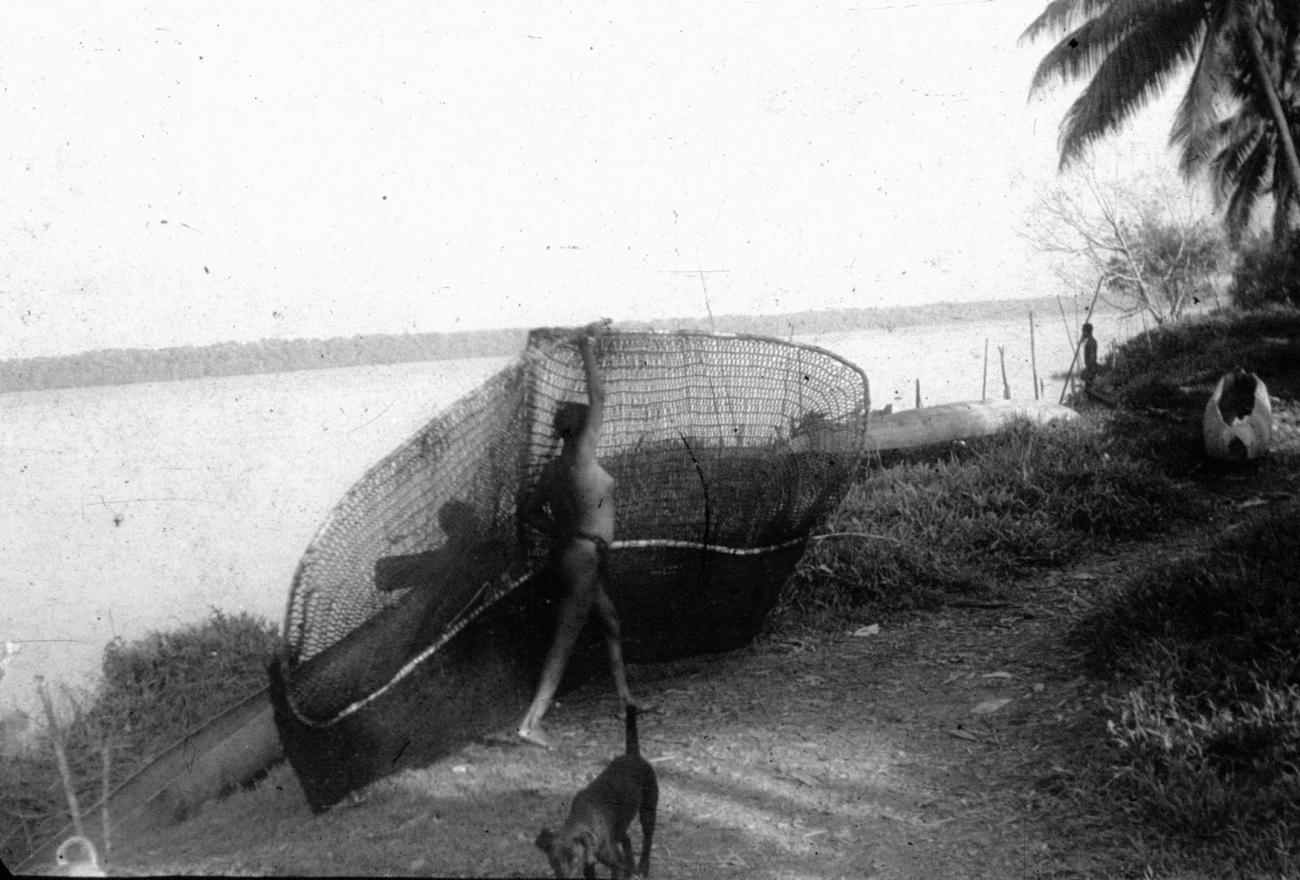 BD/216/245 -
Vrouw draagt visnet langs de rivieroever