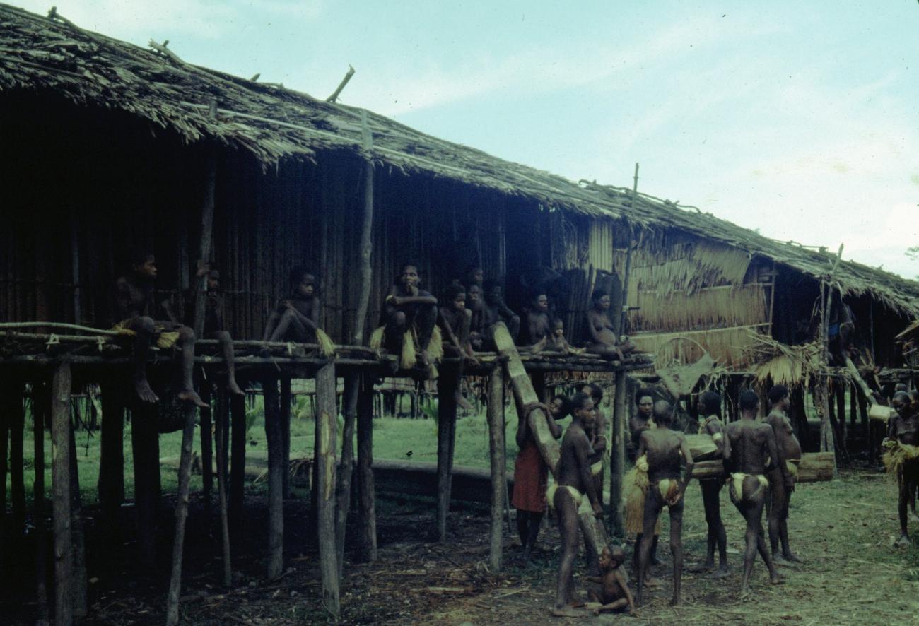 BD/216/353 -
Paalwoning in het dorp met vrouwen en kinderen op de waranda en voor het huis