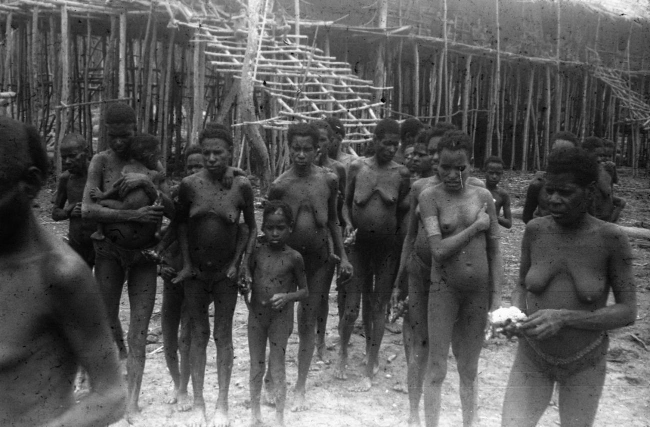 BD/216/55 -
Vrouwen en kinderen uit de Asmat voor huis op palen