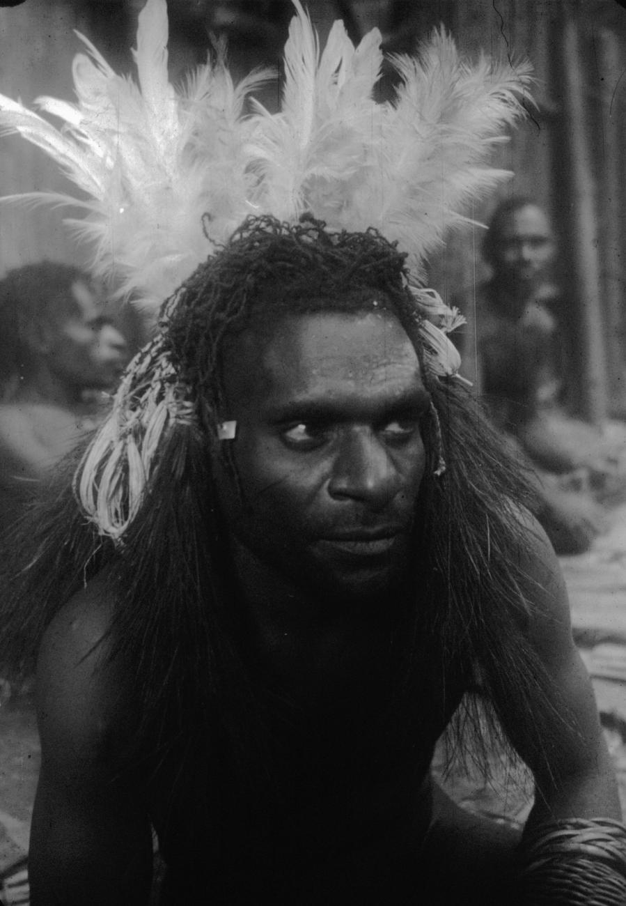BD/216/64 -
Man uit Asmat met veren hoofdtooi en armband