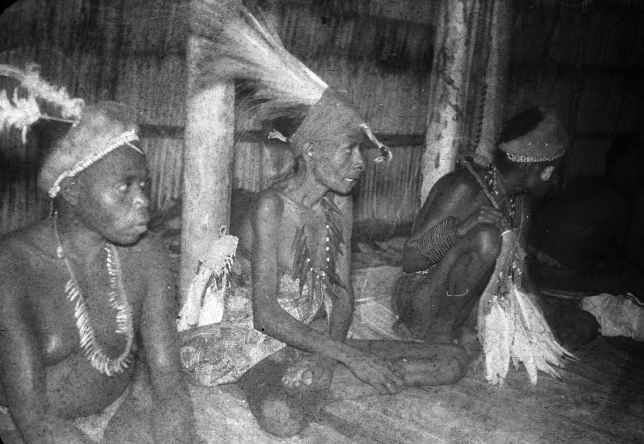 BD/216/69 -
Drie vrouwen uit de Asmat met hoofdtooi, kettingen en rituele dansstok