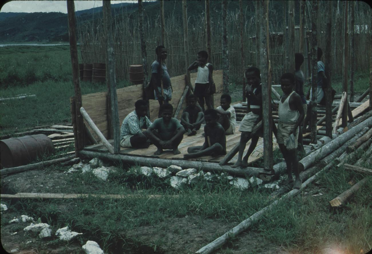 BD/248/165 -
groep zittende mannen in het skelet van te bouwen huis