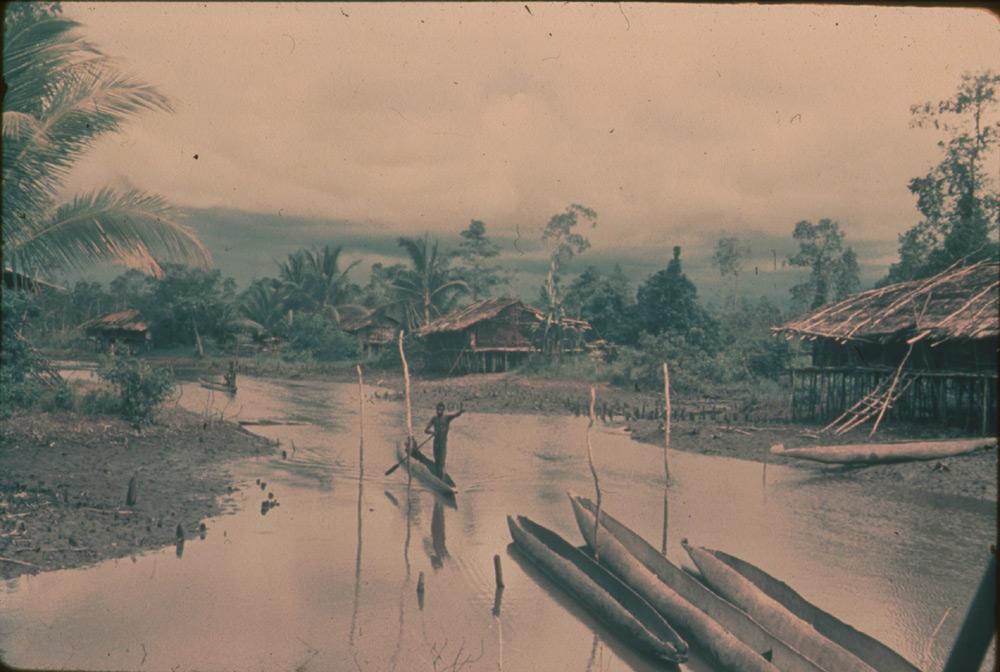 BD/30/40 - 
Stilthouses along a river with praus sailing on it
