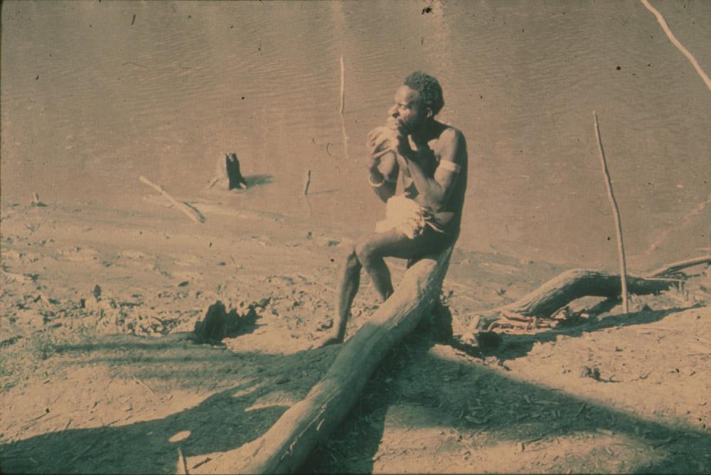 BD/30/50 -
Man eating on a trunk at the river shore