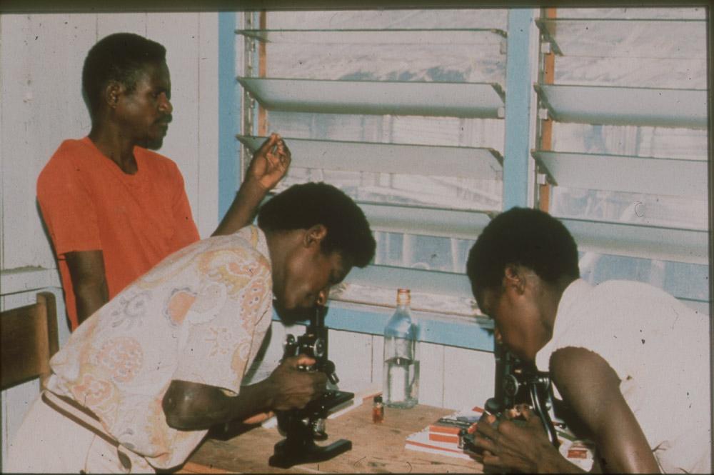 BD/30/84 - 
Asmat man and woman looking through microscopes at the medical center
