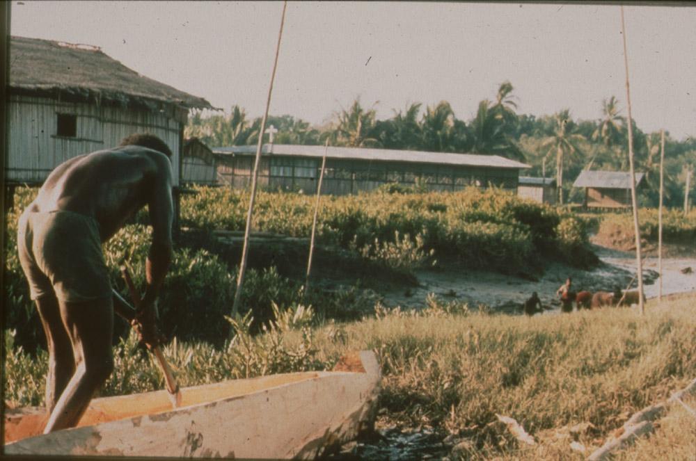 BD/30/91 - 
Asmat man carving a prau on the shore in front of the village
