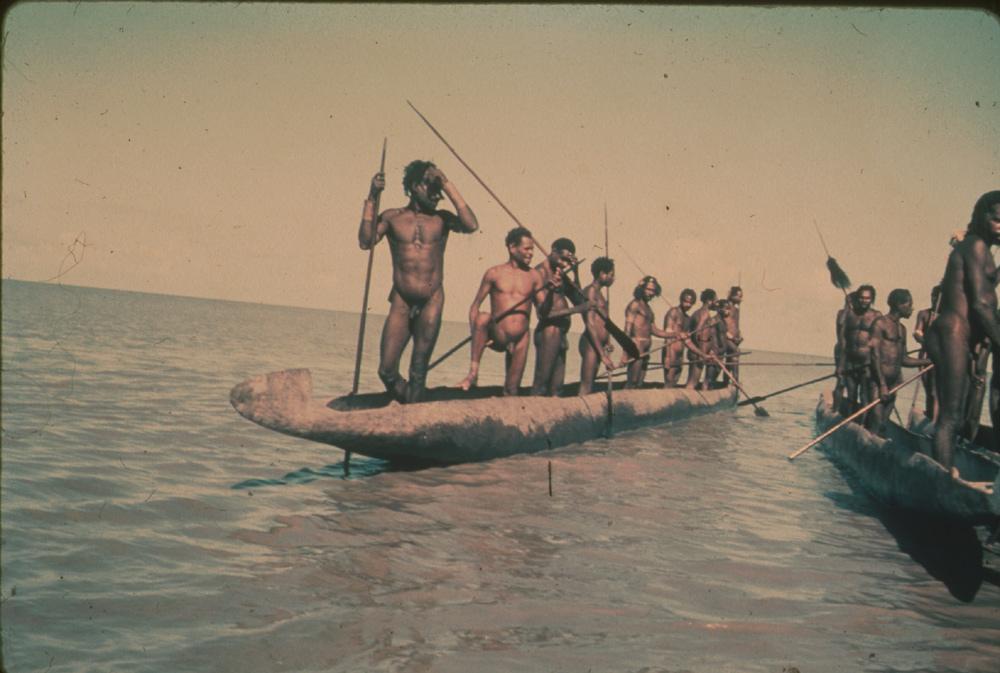 BD/30/9 - 
Asmat man armed with spears on sea in three praus
