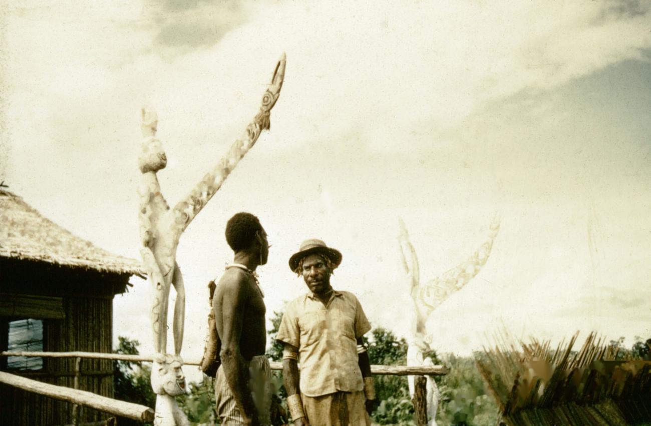 BD/66/25 - 
Twee mannen bij een geestenpaal, bisjpaal, uit de Asmat 
