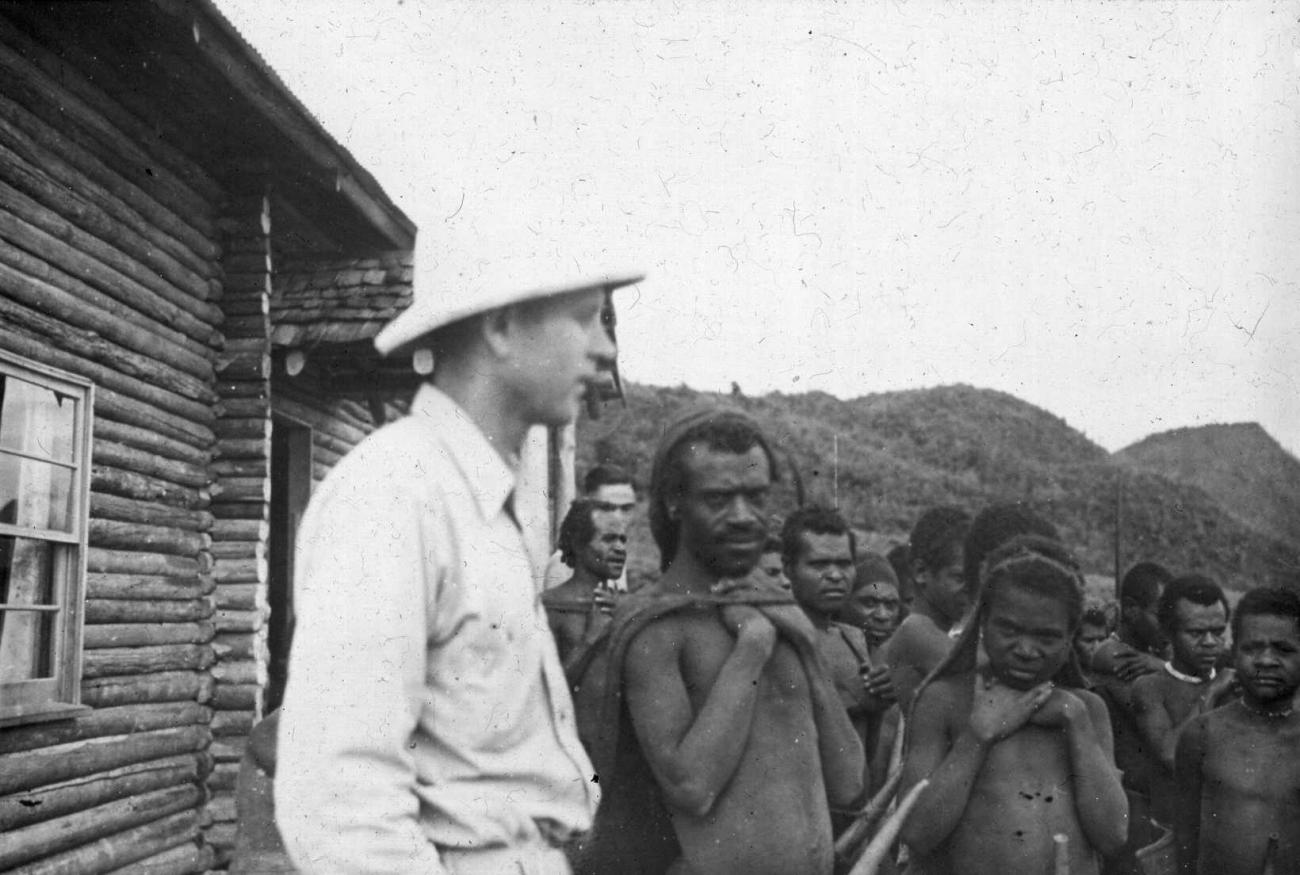 BD/66/454 - 
De Amerikaanse CAMA-zendeling K.E. Troutman samen met een groep Ekari&#039;s voor zijn blokhut bij Enarotali, Wisselmeren
