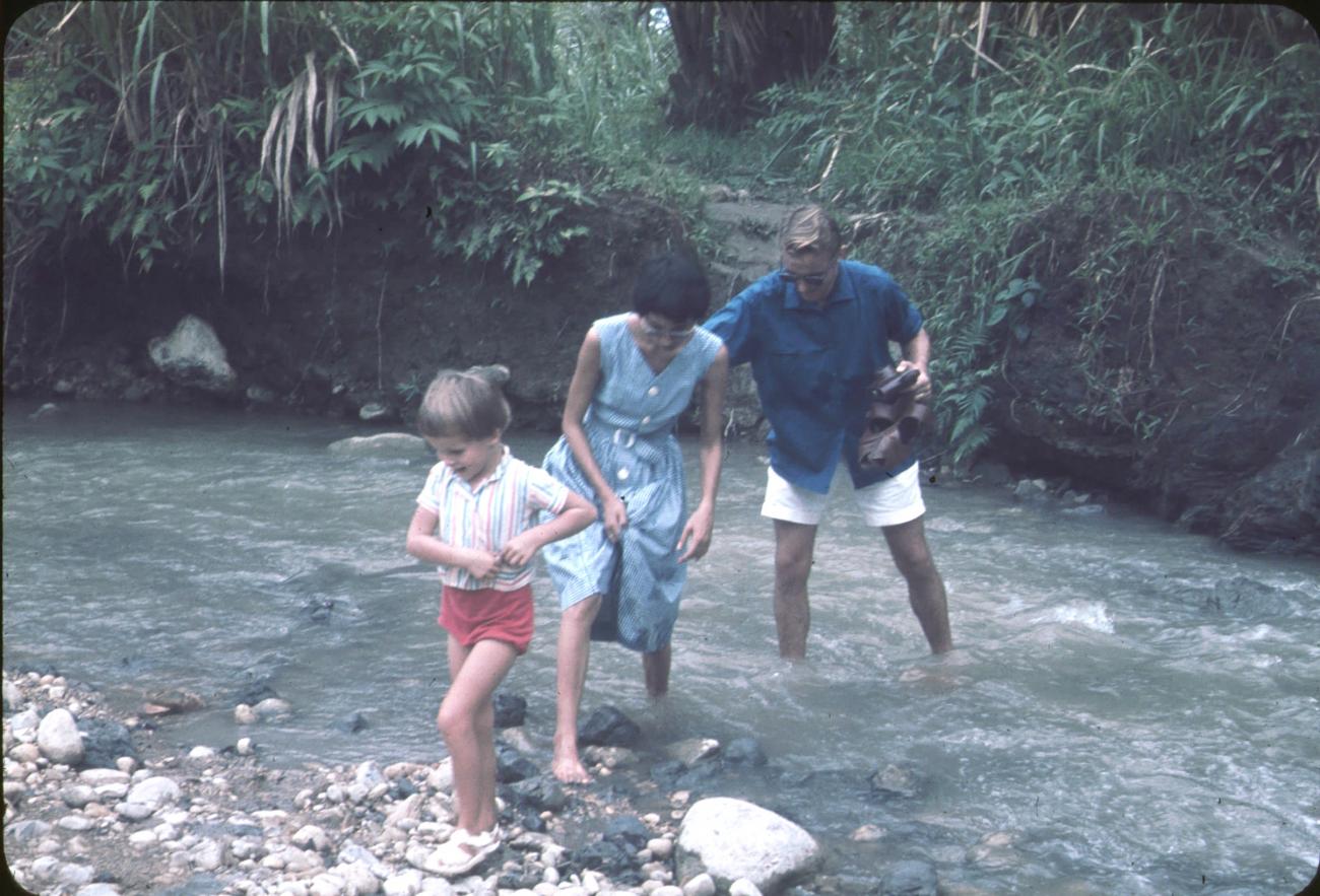 BD/171/280 -
Westerse man, vrouw en kind waden door rivier.