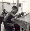 BD/245/9 Op school: jongen schrijvend op lei.