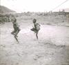 BD/329/40 Twee Papoea-mannen voeren een dans uit onder toezien van stamgenoten
