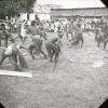BD/329/41 Papoea-mannen met omslagdoeken geven een opvoering (een soort gevechtsdans) voor een publiek