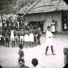 BD/329/42 Groep Papoea-jongeren,deels westers gekleed, voert een soort dans uit