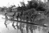 BD/216/247 Jonge Asmatters met prauw op rivier met zicht op rivieroever en paalwoning