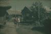BD/309/292 Twee mannen lopen op straat met traditionele paalwoningen in Ransiki